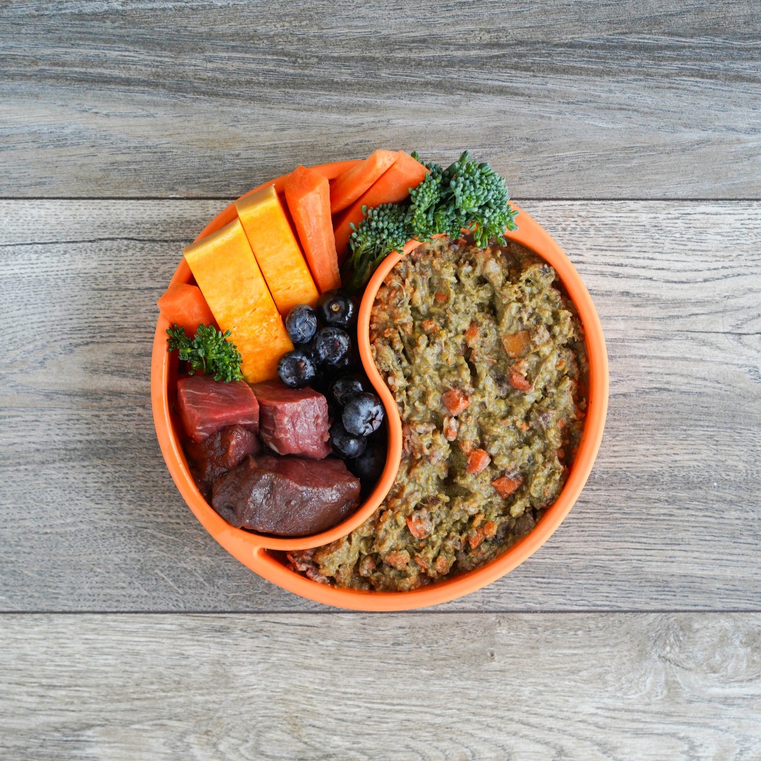 Bowl of darcy and teds raw dog food with vegetables on a wooden surface