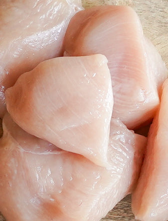 Raw chicken breast pieces on a wooden surface