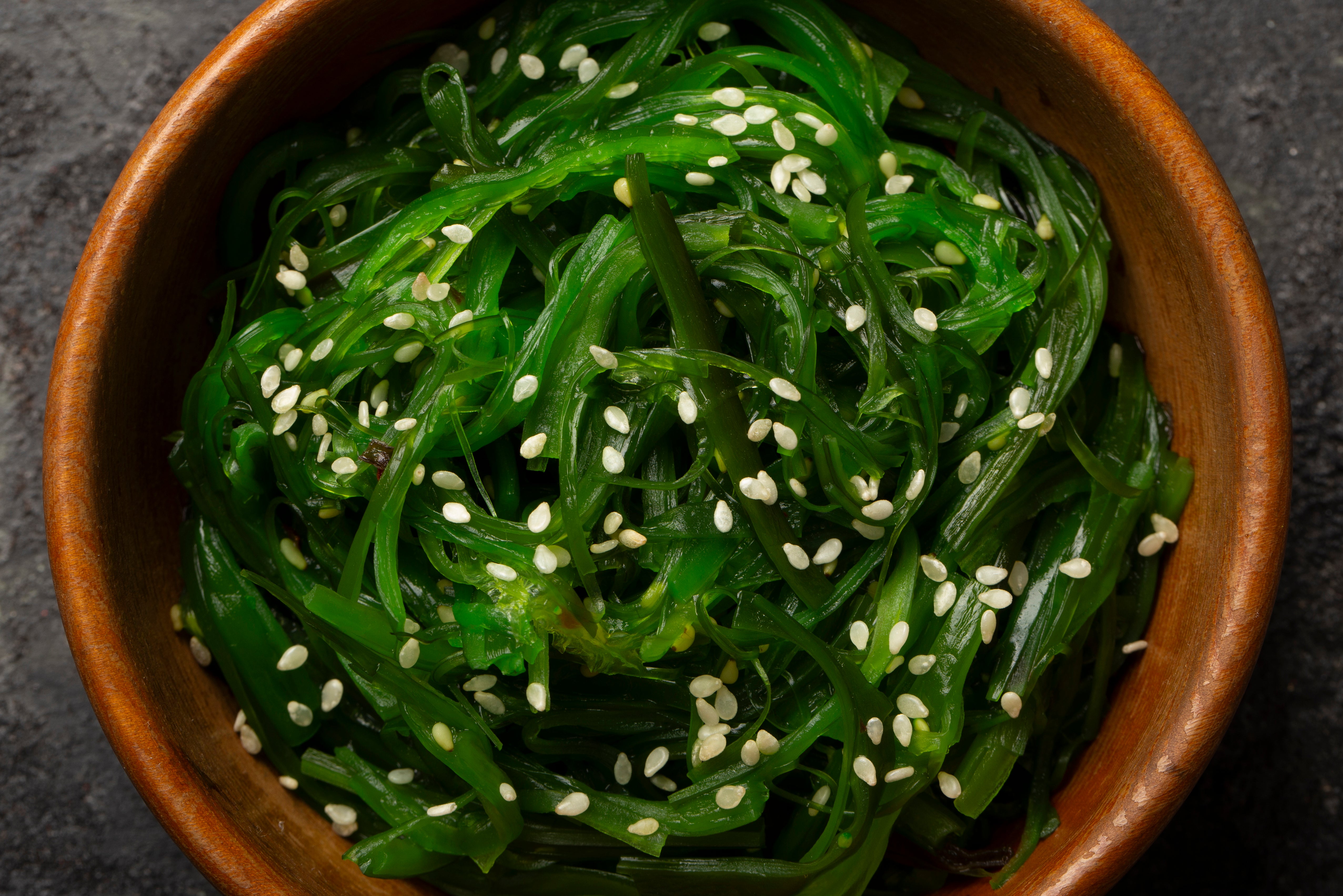 Sea kelp with sesame seeds in a wooden bowl on a dark background