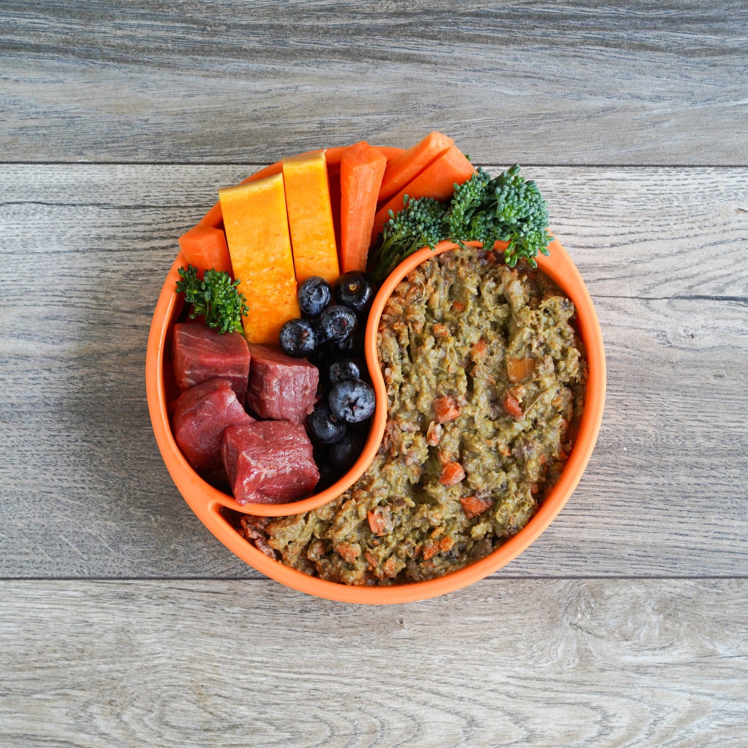 Dog food bowl with raw dog food food and vegetables and raw meat.
